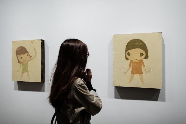 A visitor looks at the artworks by Japanese artist Yoshitomo Nara, during an exhibition in Hong Kong, on March 11, 2015