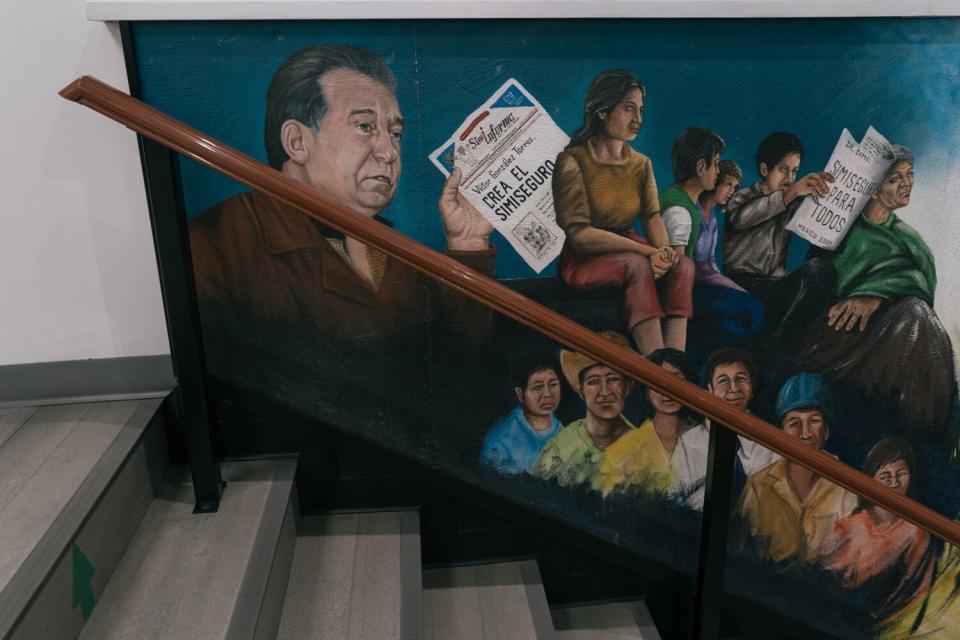 A mural along a set of stairs depicts a man holding a note near other people