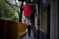 FILE PHOTO: A man wearing a face mask walks next to barriers set up to block buildings from a street in Wuhan