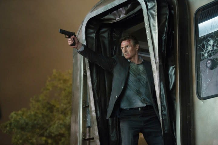 Liam Neeson points a gun on a train in The Commuter.