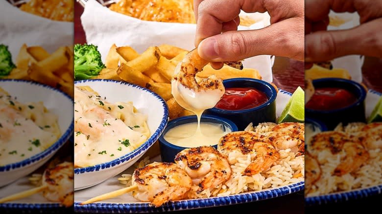 Hand holding shrimp and dipping in sauce