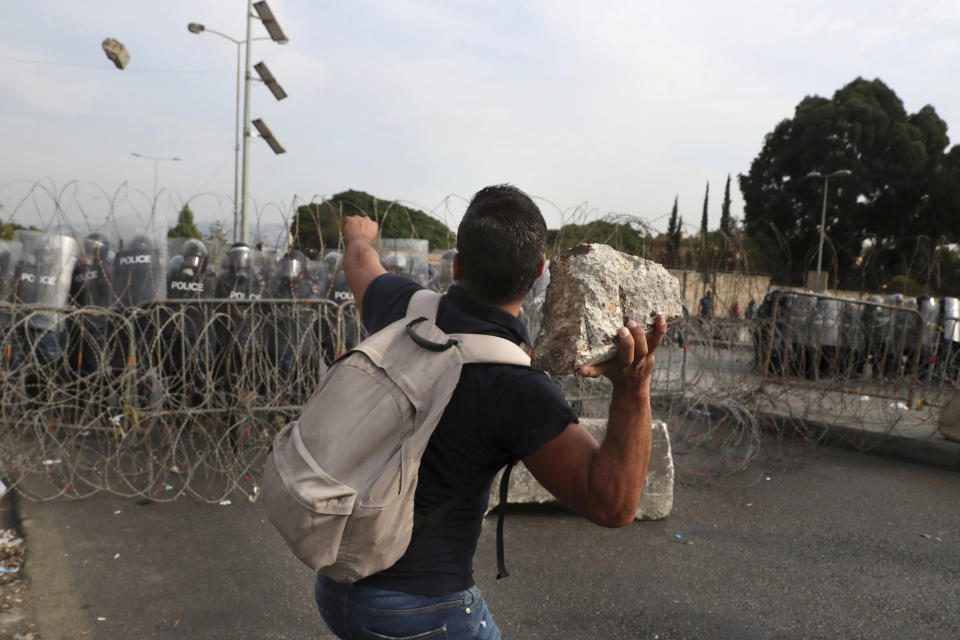 A protester throws a stone towards riot police during a protest against French President Macron's comments over Prophet Muhammad caricatures, near the Pine Palace, which is the residence of the French ambassador, in Beirut, Lebanon, Friday, Oct. 30, 2020. A few hundred demonstrators held a protest called for by a Sunni Islamist party, Hizb ul-Tahrir, against French cartoons of the Prophet Muhammad. (AP Photo/Bilal Hussein)