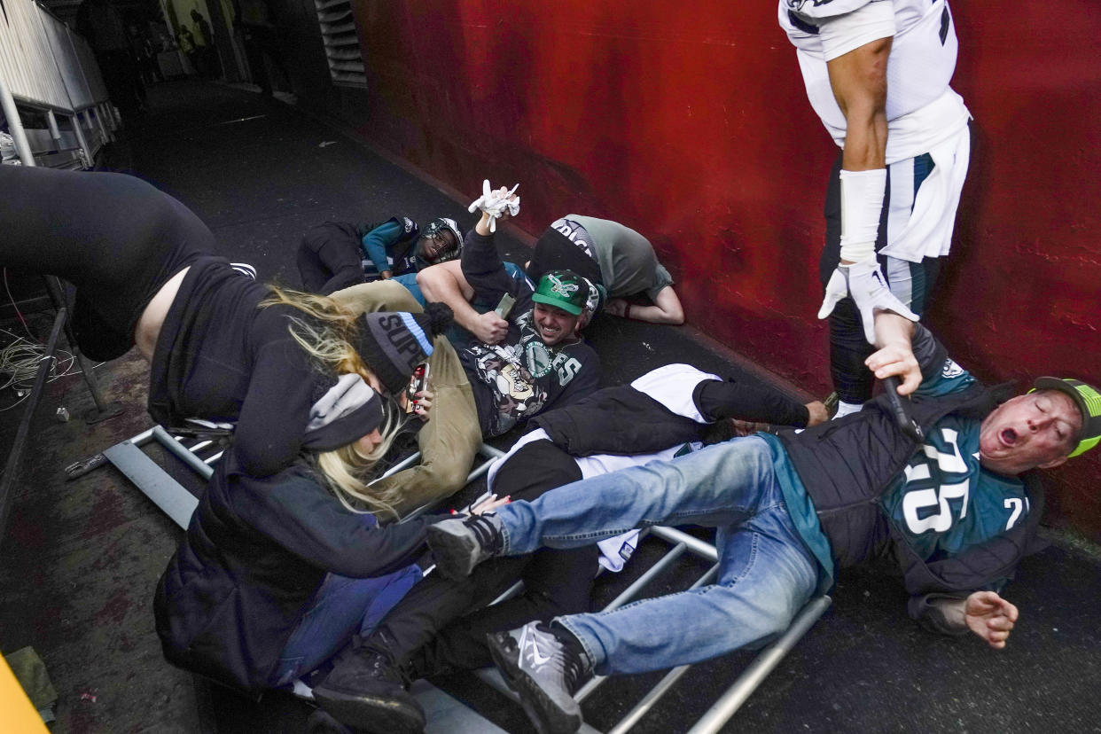 Fans lay on the ground after a railing collapsed causing them to fall towards Philadelphia Eagles quarterback Jalen Hurts (1) at the end of an NFL football game, Sunday, Jan. 2, 2022, in Landover, Md. Philadelphia won 20-16. (AP Photo/Alex Brandon)