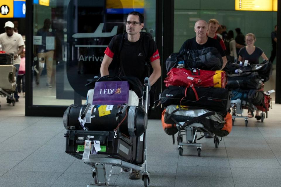 Diver Chris Jewell, left, from the rescue mission, which helped to save 12 schoolboys and their football coach from a flooded cave in Thailand, arrives back at London's Heathrow Airport (PA)