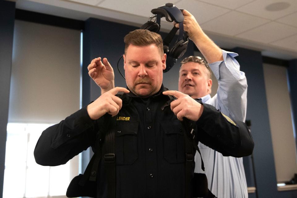 Capt. Robert Milligan helps Sgt. Mark Bolender put on the virtual reality set before they demonstrate the department's new virtual reality de-escalation training setup at Central Bucks Police Department building in Pennsylvania on Thursday, Nov. 3, 2022.