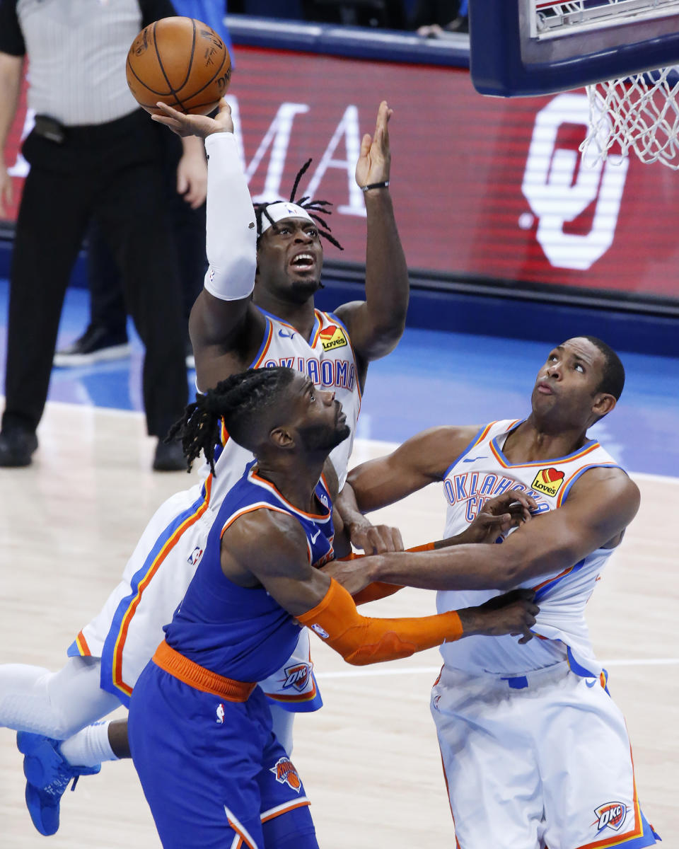Oklahoma City Thunder forward Luguentz Dort (5) takes a shot against New York Knicks center Nerlens Noel (3), guarded by Oklahoma City Thunder center Al Horford (42), during the first half of an NBA basketball game, Saturday, March 13, 2021, in Oklahoma City. (AP Photo/Garett Fisbeck)