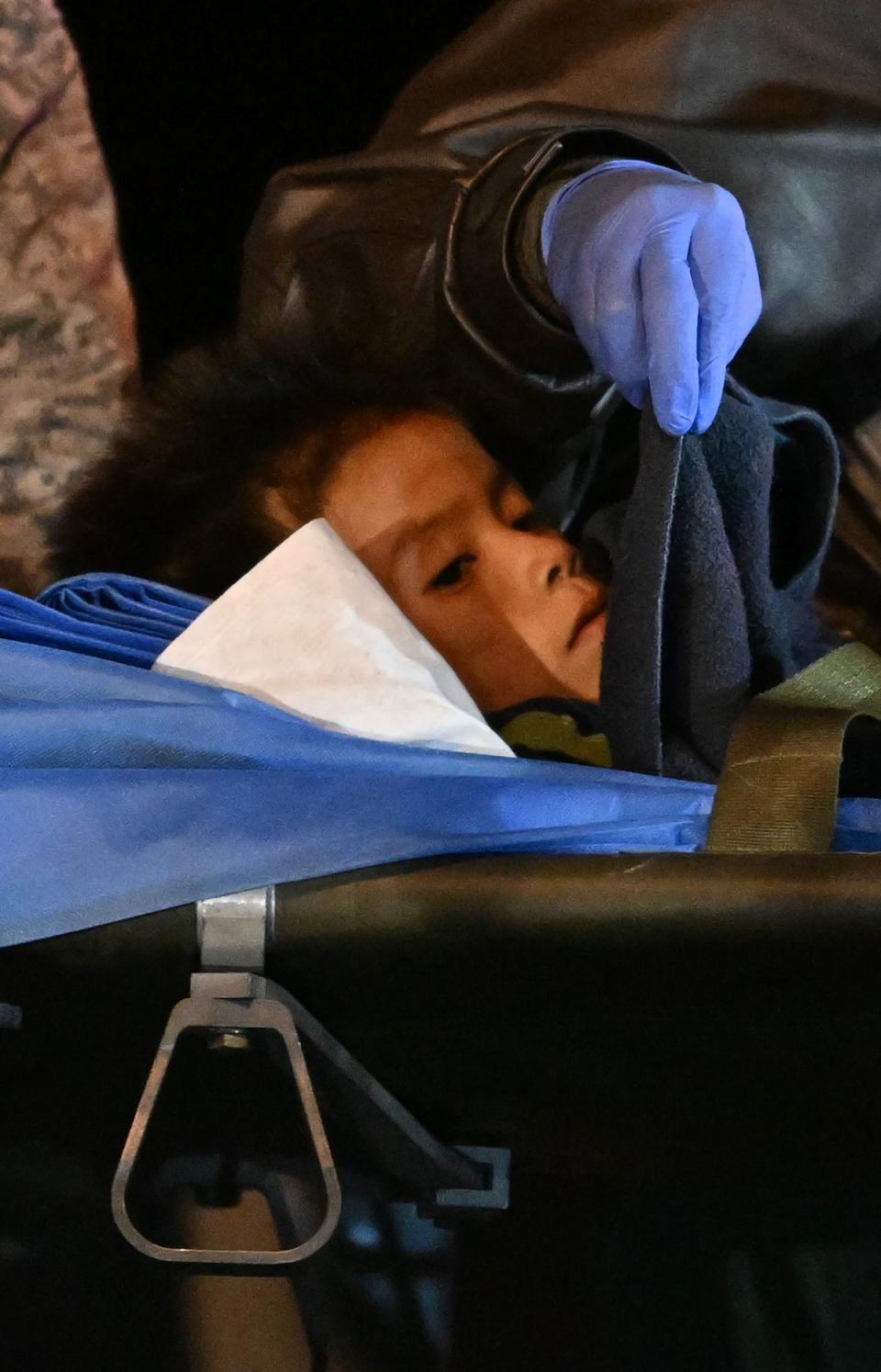 One of the four Indigenous children who were found alive after being lost for 40 days in the Colombian Amazon forest following a plane crash, is stretchered out of a plane upon landing at the CATAM military base in Bogota on 10 June 2023. (AFP via Getty Images)