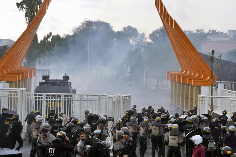 Riot police officers fire tear gas to disperse soccer supporters outside Jatidiri Stadium in Semarang, Central Java, Indonesia, Friday, Feb. 17, 2023. Indonesian police fired tear gas to disperse fans who were trying to force their way into a match that was held without spectators, months after the use of tear gas in another stadium in East Java caused one of the world's worst sporting disasters. (AP Photo/Adhik Kurniawan)