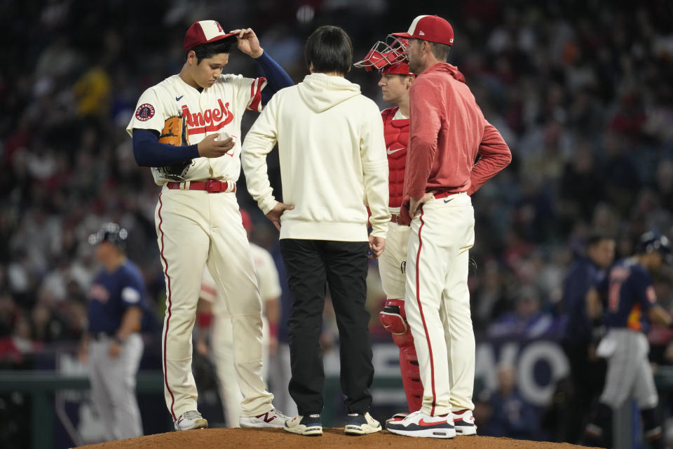 Los Angeles Angels starting pitcher Shohei Ohtani (17) is visited on the mound by interpreter Ippei Mizuhara, center, catcher Chris (39), and pitching coach Matt Wise, right, during the fifth inning of a baseball game against the Houston Astros in Anaheim, Calif., Tuesday, May 9, 2023. (AP Photo/Ashley Landis)