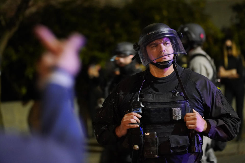 A protestor reacts towards a Portland police officer during protests, Saturday, Sept. 26, 2020, in Portland. The protests which began since the police killing of George Floyd in late May often result frequent clashes between protesters and law enforcement. (AP Photo/John Locher)