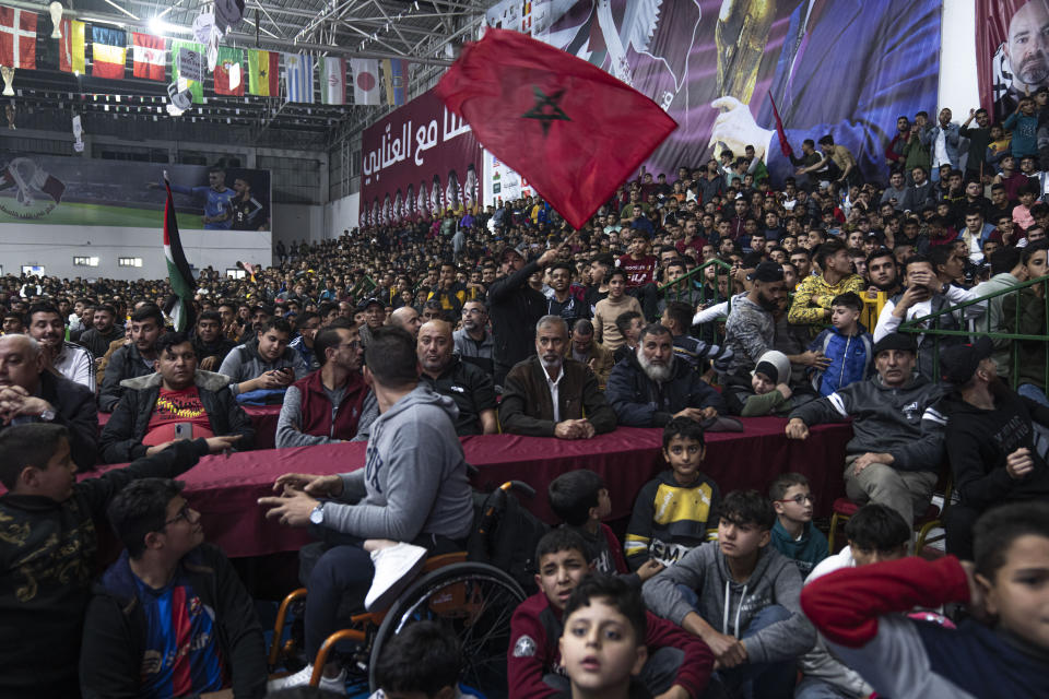 FILE - Palestinians wave Moroccan and their national flags as they watch a live broadcast of the World Cup quarterfinal soccer match between Morocco and Portugal played in Qatar, in Gaza City Saturday, Dec. 10, 2022. It's a rare moment in the Middle East when the public's voice roars louder than those of the governments. But Morocco's surprise wins at the World Cup have stirred a joy and pride among many Arab fans that have, at least for a moment, eclipsed the region's many political divisions. (AP Photo/Fatima Shbair, File)