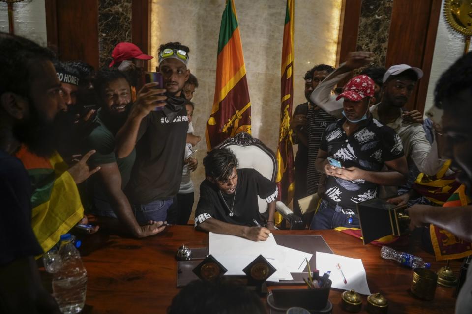 A protester sits on a chair surrounded by others after storming the Sri Lankan Prime Minister Ranil Wickremesinghe's office, demanding he resign after president Gotabaya Rajapaksa fled the country amid economic crisis in Colombo, Sri Lanka, July 13, 2022. The image was part of a series of images by Associated Press photographers that was a finalist for the 2023 Pulitzer Prize for Breaking News Photography. (AP Photo/Rafiq Maqbool)