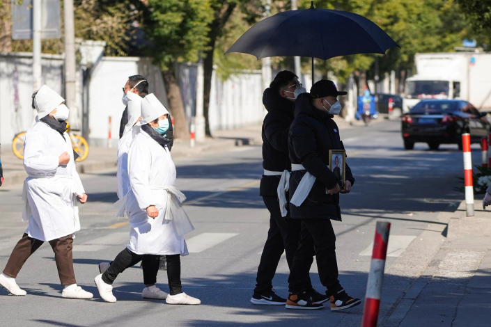 A man wearing a protective mask holds a picture frame of a loved one outside a funeral home, as coronavirus disease (COVID-19) outbreaks continue, in Shanghai, China, December 23, 2022. REUTERS/Aly Song