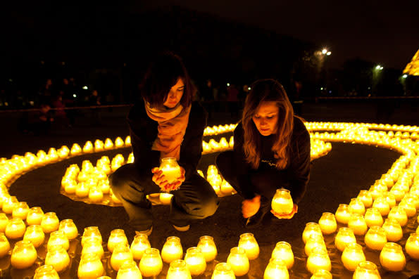 Earth Hour 2010. Two volunteers holding a candle amongst the 1600 candles, symbols of the 1600 pandas and forming the shape of a 60 to celebrate Earth Hour, place Jacques Rueff, Eiffel Tower, Paris, France.