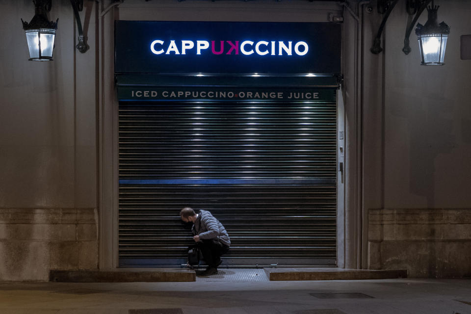 An employee closes his cafeteria before curfew in Barcelona on Monday, Oct. 26, 2020. Spain orders nationwide curfew to stem worsening outbreak. Spanish Prime Minister Pedro Sánchez has declared a second nationwide state of emergency in hopes of stemming a resurgence in coronavirus infections. (AP Photo/Emilio Morenatti)