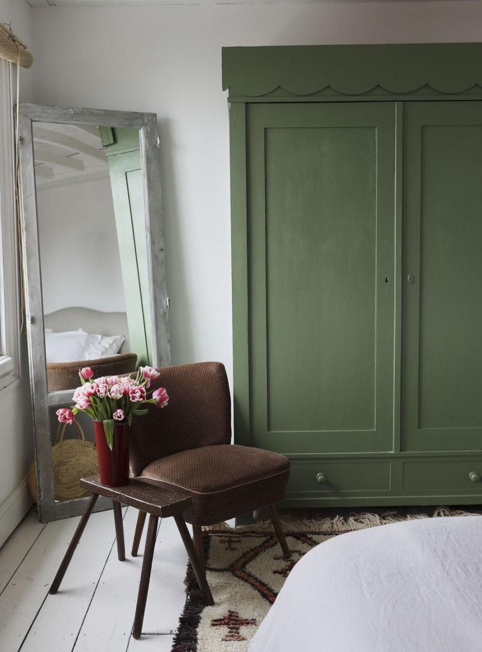 <p>"I found this old wardrobe at an antique fair and painted it Farrow & Ball Calke Green and added the scalloped edging that I found in a junk shop - it used to be an old curtain pelmet. The floors and walls are painted bright, matt white. </p><p>The Moroccan Bedouin rug I had in my shop and it never sold because it's so big, so it came home with me. The cocktail chair and stool are both Ardingly Antique Fair finds. The floor mirror is a vintage door thats been re glazed with mirror instead of glass."</p>