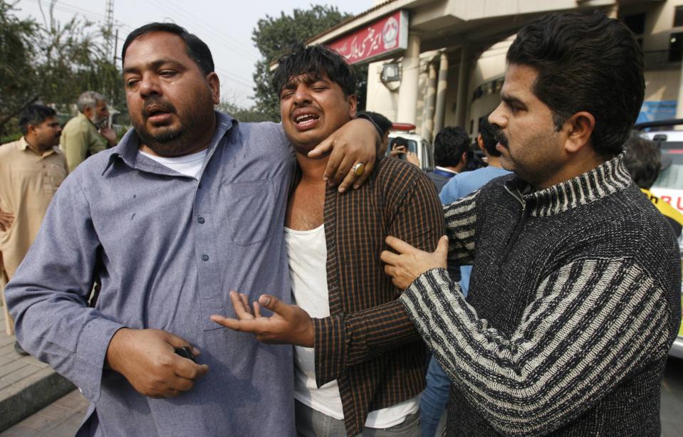 Men mourn the death of a relative, who was killed in an explosion outside the police headquarters, at hospital in Lahore