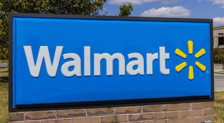 The blue, white, and yellow Walmart (WMT) logo is being displayed on a small rectangle sign in the grass.