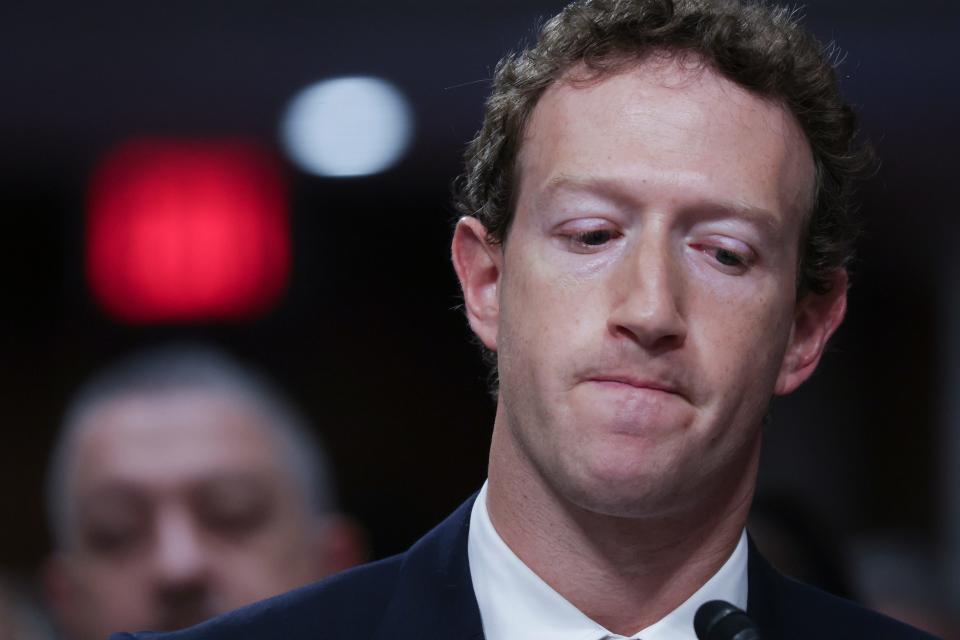 Mark Zuckerberg looking down whilst wearing a suit