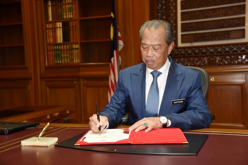 Malaysia’s Prime Minister Muhyiddin Yassin signs a document on his first day at the prime minister's office in Putrajaya