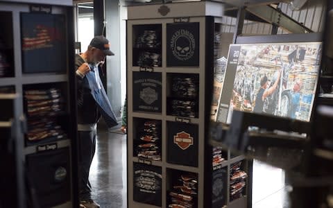 A man tries on a t-Shirt in the gift shop of the Harley Davidson's vehicle and powertrain operations plant in Kansas City - Credit: Neville Elder for The Telegraph