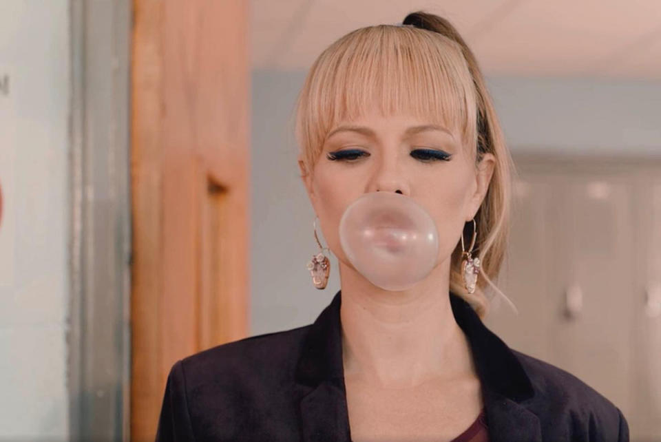 Tammin Sursok with blonde bangs and a high ponytail blows a bubble with her gum