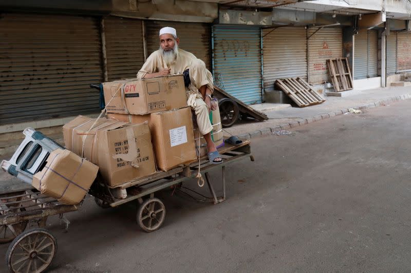 A labourer sits with supplies outside a closed market during a contrywide strike in Karachi,