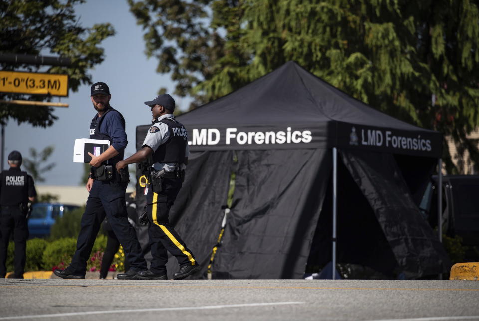 RCMP officers talk as a tent covers a body at the scene of a shooting in Langley, British Columbia, Monday, July 25, 2022. Canadian police reported multiple shootings of homeless people Monday in a Vancouver suburb and said a suspect was in custody. (Darryl Dyck/The Canadian Press via AP)
