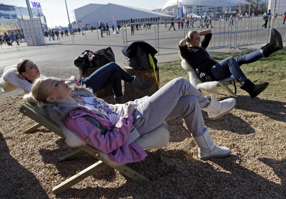 Women lay in the sun outside the Swiss House at the 2014 Winter Olympics, Wednesday, Feb. 12, 2014, in Sochi, Russia. Temperatures are predicted near 60 degrees Fahrenheit in Sochi on Wednesday. (AP Photo/Morry Gash)