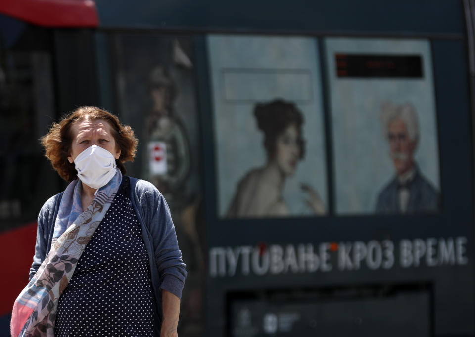 A woman wearing a face mask to protect against coronavirus walks in downtown Belgrade, Serbia, Monday, July 13, 2020. Health authorities are warning that Serbian hospitals are almost full due to the latest surge. (AP Photo/Darko Vojinovic)