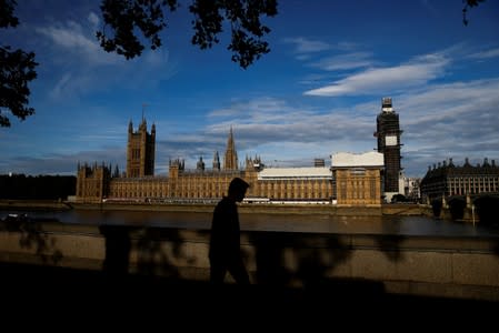 The Houses of Parliament can be seen as a man walks along the South Bank in London