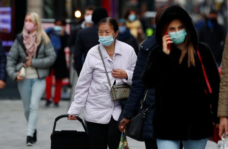 People wearing protective masks walk in a shopping street amid the coronavirus disease outbreak in Brussels