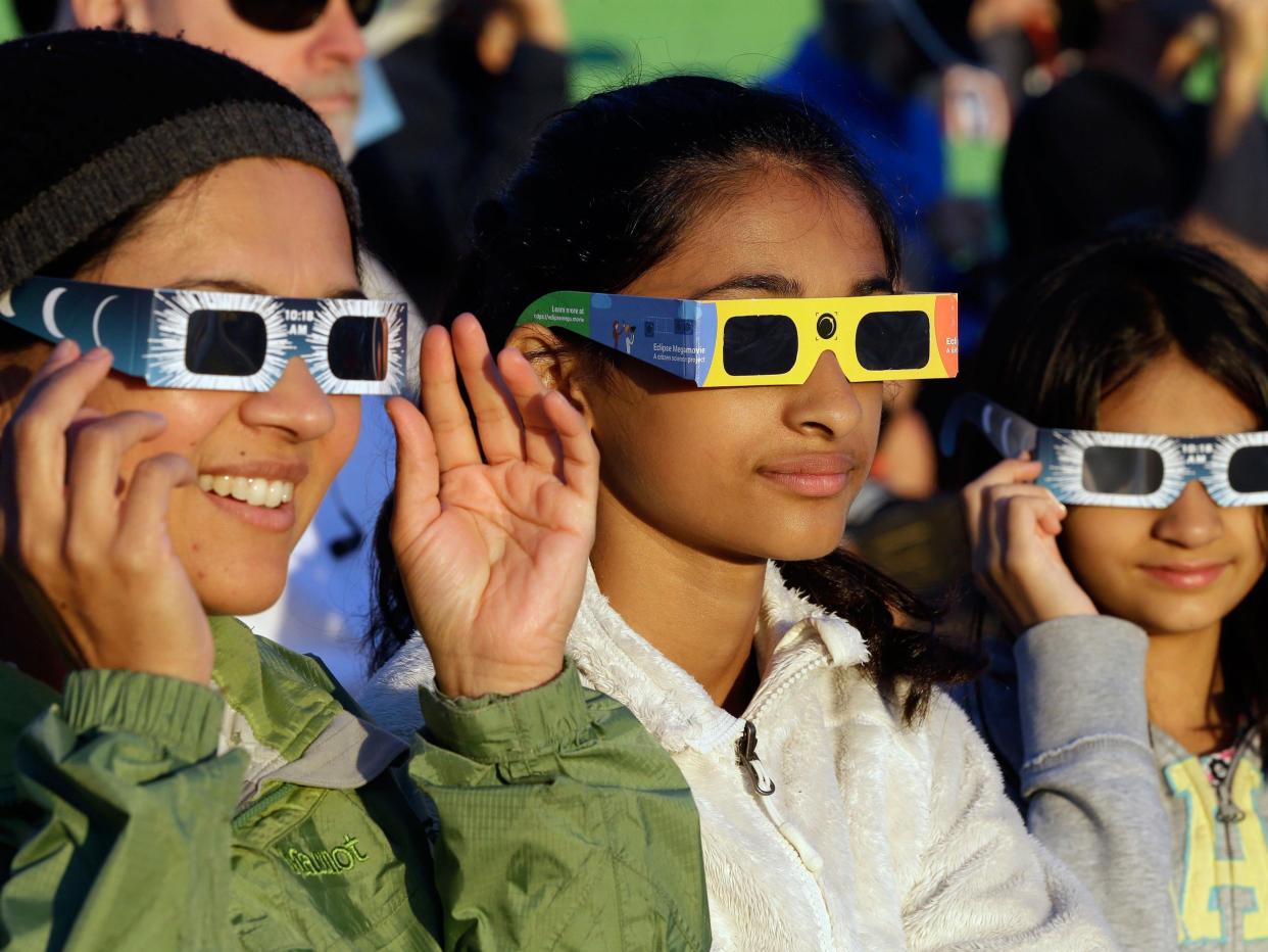 Visitors from Seattle try out their eclipse glasses on the sun at a gathering of eclipse viewers in Salem, Oregon: AP