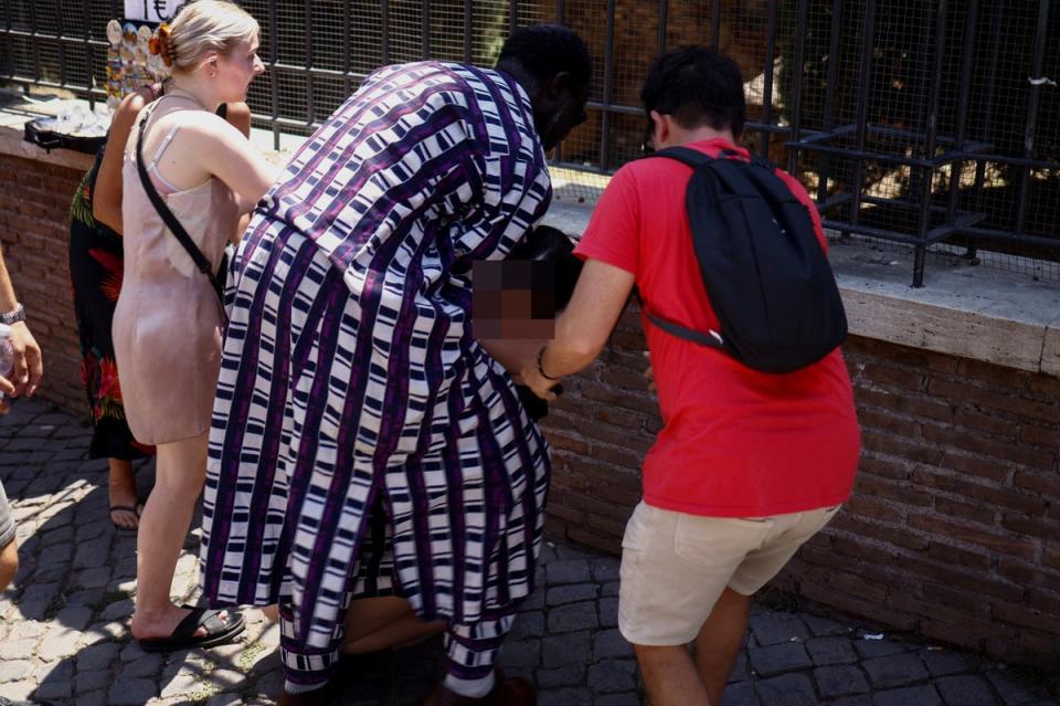A tourist from the UK receives help near the Colosseum in Rome after fainting during the heatwave on July 11 (REUTERS)