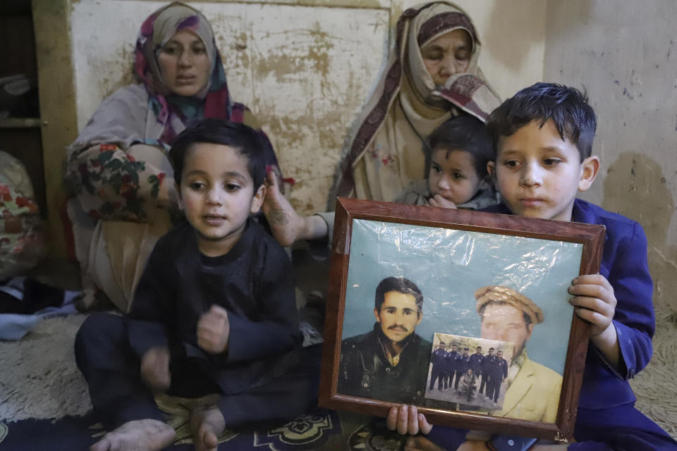 Children of Mohammed Hassan, a Pakistani porter who died on July 27 during a summit of K2, sit together with a portrait of their father and grandfather, accompanied by Hassan's mother, third left, and wife at their home in Tasar, a village in the Shigar district in the Gilgit-Baltistan region of northern Pakistan, Saturday, Aug. 12, 2023. An investigation has been launched into the death of a Hassan near the peak of the world's most treacherous mountain, a Pakistani mountaineer said Saturday, following allegations that dozens of climbers eager to reach the summit had walked past the man after he was gravely injured in a fall. (AP Photo/M.H. Balti)