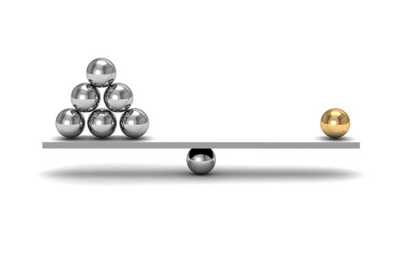 One gold sphere balancing against six silver spheres on a balance beam.