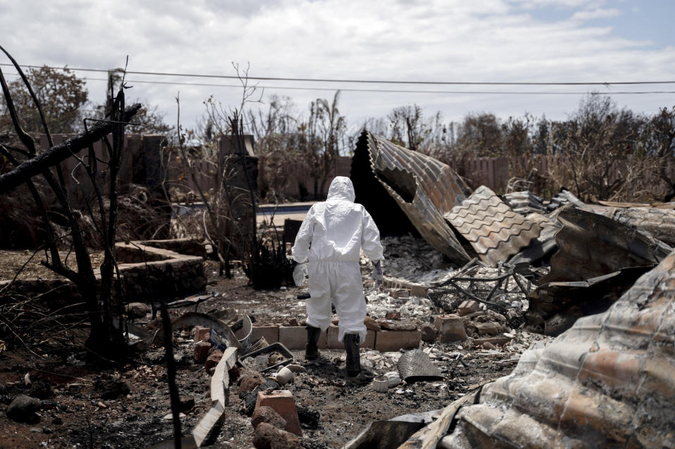 CORRECTS SPELLING OF LAST NAME TO VIERRA INSTEAD OF VERA - Leola Vierra walks through the remains of her home for the first time, Tuesday, Sept. 26, 2023, in Lahaina, Hawaii. The Vierras are among the couple dozen residents who are able to return to their property in Zone 1-C following August's deadly wildfire. Authorities in Maui strongly encouraged homeowners to wear protective gear provided by nonprofit groups when visiting their properties to protect against asbestos, lead and other toxic remains of the wildfire. (AP Photo/Mengshin Lin)