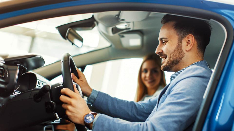 Young couple choosing new car for buying in dealership shop.