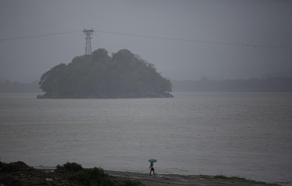 An Indian fisherman walks in the middle of heavy wind and rain along the river Brahmaputra in Gauhati, India, Thursday, May 21, 2020. A powerful cyclone ripped through densely populated coastal India and Bangladesh, blowing off roofs and whipping up waves that swallowed embankments and bridges and left entire villages without access to fresh water, electricity and communications. (AP Photo/Anupam Nath)