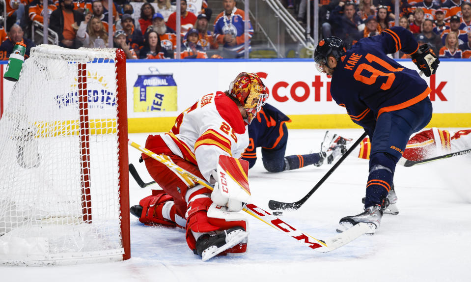 Calgary Flames goalie Jacob Markstrom, left, lets in a goal from Edmonton Oilers winger Evander Kane during the second period of an NHL hockey Stanley Cup second-round playoff series game in Edmonton, Alberta, Sunday, May 22, 2022. (Jeff McIntosh/The Canadian Press via AP)