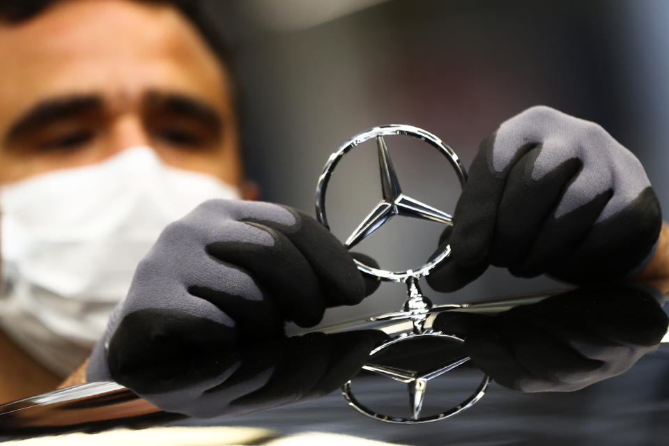 FILE - In this Thursday, April 30, 2020 file photo, an employee attaches a Mercedes emblem as he works on a Mercedes-Benz S-class car at the Mercedes plant in Sindelfingen, Germany. Daimler, maker of Mercedes-Benz vehicles, is reporting third-quarter earnings on Friday Oct. 22, 2020. (AP Photo/Matthias Schrader, file)