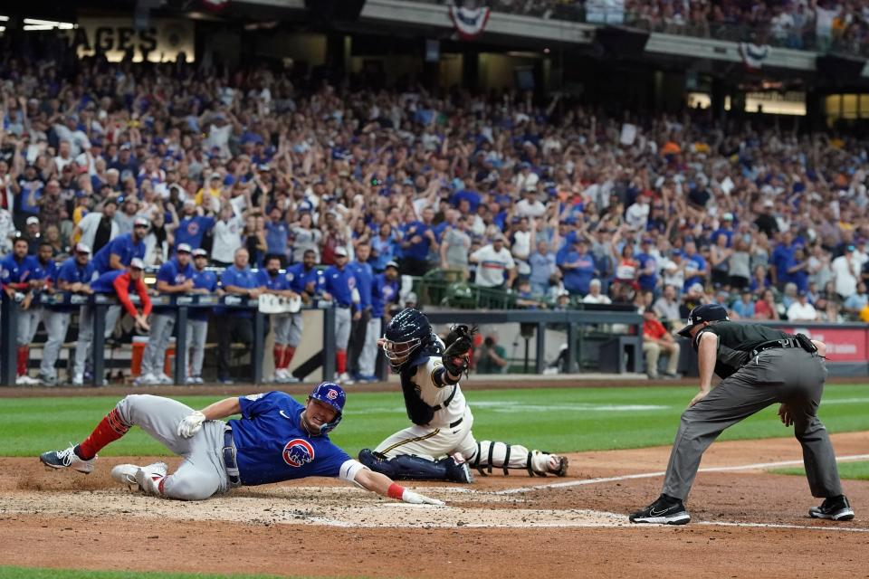 Seiya Suzuki slides safely past Brewers catcher Victor Caratini as he scores on an inside-the-park home run for the Cubs in the top of the ninth inning Monday.