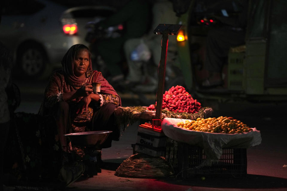 A woman, who sells fruit to earn a living for her family, waits for customers along roadside, in Lahore, Pakistan, Tuesday, March 7, 2023. Pakistan is observing the International Women's Day with other nations. (AP Photo/K.M. Chaudary)