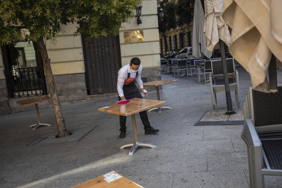 El camarero Miguel Santana desinfecta una mesa antes de abrir la terraza de un bar en Madrid el miércoles, 30 de septiembre del 2020. (AP Foto/Bernat Armangue)