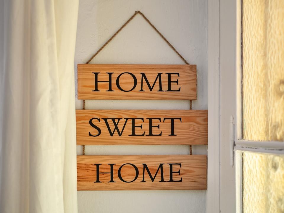 A wooden sign that says "home sweet home" hanging on wall