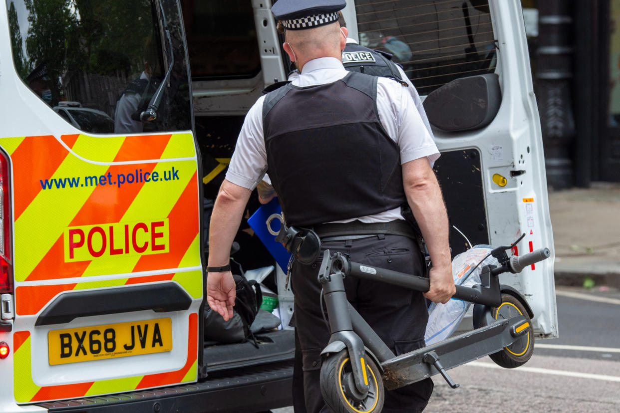 A police officer puts a confiscated electric scooter into a police van after having stopped a male for riding it in London. (PA)