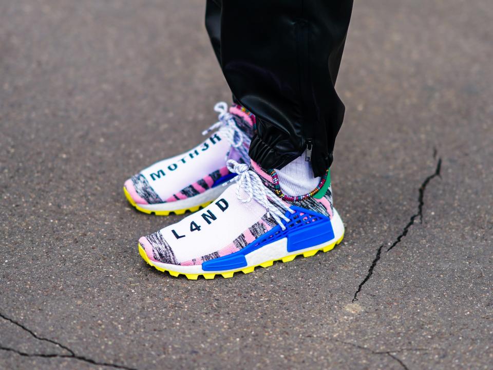 A guest wears Pharrell Williams x Adidas NMD HU Solarhu ‘MOTH3R & L4ND’