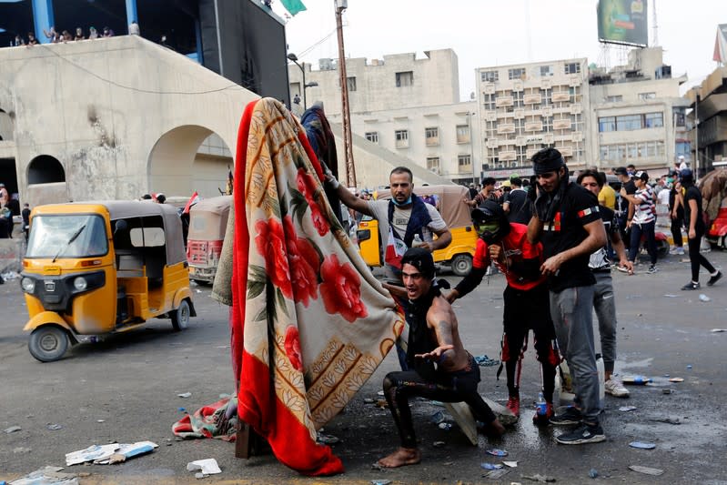 Demonstrators react during a protest over corruption, lack of jobs, and poor services, in Baghdad