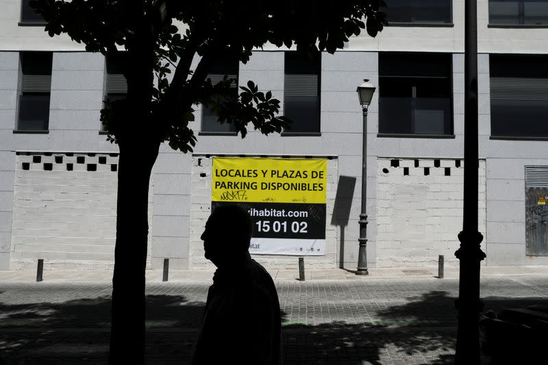 FILE PHOTO: A man walks past a sign that reads "Properties and parking available" on the wall of an apartment complex in Madrid