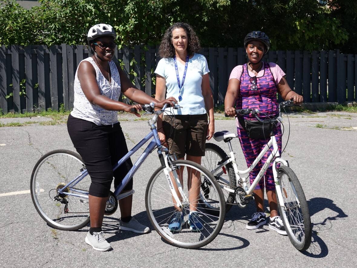 Claire Kiruhira, left, and Christine Uwamwezi, far right, pose with their Vanier Vélo instructor Denise Inglis. It's never too late to learn a new skill, says Inglis. (Giacomo Panico/CBC - image credit)